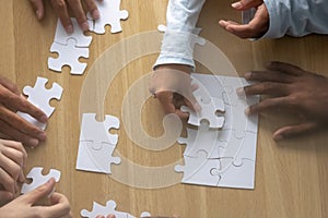 Top above close up view multiracial human hands assembling puzzle