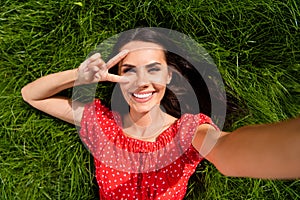 Top above high angle view of cheerful woman make selfie lie grass show v-sign in park outside outdoors