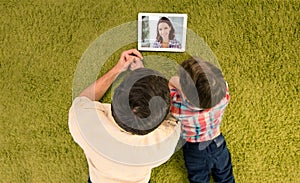 Top above high angle view of happy smiling father and small son lying on green carpet talking to mom using modern