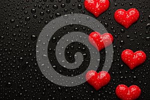 Top above overhead close up view photo image of red hearts on black backdrop with drops