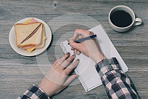 Top above overhead close up view photo of woman`s hand writing in notepad book story list idea inspiration organizer notebook. B