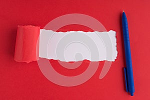 Top above overhead flat lay view photo of blue ballpoint pen torn red paper over white background with copyspace