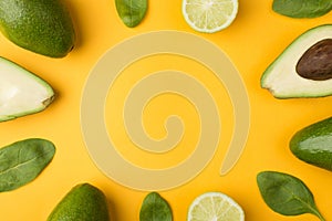 Top above overhead view cropped photo of cut avocado, lemons and baby spinach leaves isolated on yellow background
