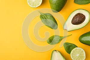 Top above overhead view cropped photo of cut avocado, lemons and baby spinach leaves places to the right side isolated on yellow