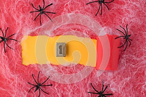 Top above overhead view photo of torn red paper and keyhole over yellow background with spiders and spiderweb