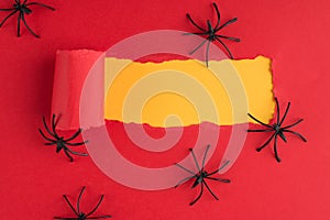 Top above overhead view photo of torn red paper over yellow background with decorative spiders