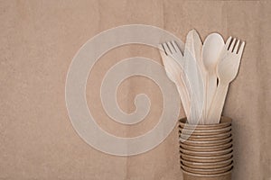 Top above overhead view photo of wooden cutlery placed inside a stack of paper cups on the right side isolated on craft paper