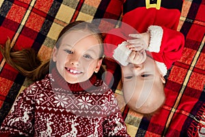 Top above view photo of kids brother sister lay plaid smile wear sweater costume in decorated x-mas home indoors