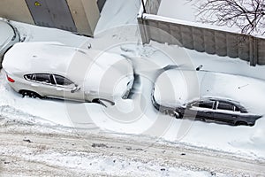 Top aerail view of apartment office building parking lot with many cars covered by snow stucked after heavy blizzard snowfall