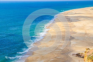 Top aerial panoramic view of sandy beach, waves of azure blue water of Atlantic Ocean and endless horizon near Nazare town
