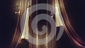 Top aerial shot of night traffic on a highway showing cars and lanes of light with bridges and viaducts
