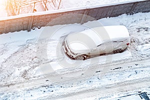 Top aerial view of apartment office building parking lot with many cars covered by snow stucked after heavy blizzard snowfall