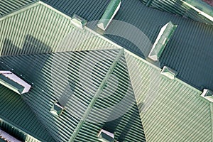 Top aerial view of building green shingle tiled roof with complex configuration construction. Abstract background, geometrical