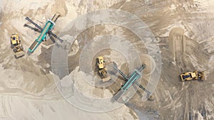 Top aerial view of bulldozer loading sand into empty dump truck in open air quarry