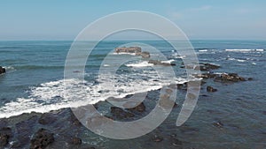 Top aerial view from flying drone above ocean landscape with big waves and rocks on black sand beach. Copy space for