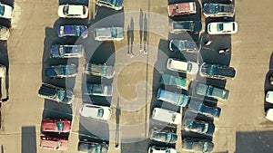 Top aerial view of many cars on a parking lot of supermarket or on sale car dealer market.