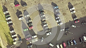 Top aerial view of many cars on a parking lot of supermarket or on sale car dealer market.