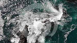 Top aerial view of ocean waves splash against rocks background,