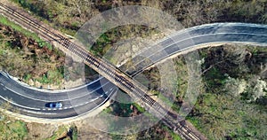 Top aerial view of a railway rails over a bridge and a beautiful forest. Landscape of a road and driving car