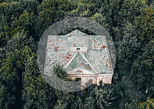 Top aerial view shot of abandoned building in impassable dense green forest.