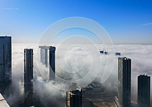 Top aerial view shot of skyscrapers in the city with fog clouds passing by - Abu Dhabi Al Reem island Sun and Sky towers