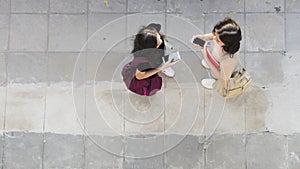 Top aerial view teen girls talk and use smart phone at pedestrian walk way