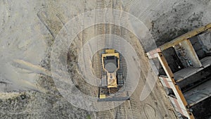 Top Aerial view on Tracked Bulldozer Rides on Sandy Road at Construction Site