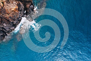 Top aerial view of turquoise Atlantic ocean water waves crashing on rocks on the Portuguese Madera island seashore photo