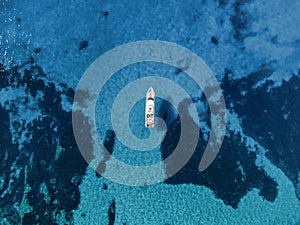 top aerial view of a yacht anchored in turquoises waters of a beach in the island of Majorca