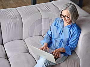 Top angle shot on couch at home of older female advanced user of ecommerce.