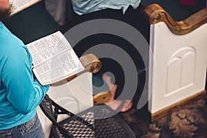 Top-angle shot of a man in a church, holding the open Bible, the concept of religion and faith