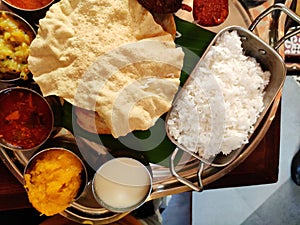 Top angle Tastey yummy south Indian lunch thali with variety of dishesh and sweet kesari curd rice parrota aplam papad lunch