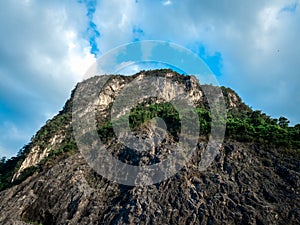 Top of beautiful peak rock mountain texture background, view from bottom. Strong cliff on blue sky and cloud backgrounds.