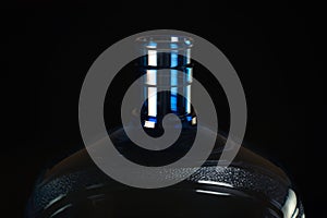 Top of big blue plastic bottle for water on black background close up