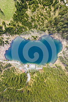 Top birds eye view to lake Frauensee surrounded of forest trees and house