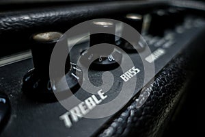 A top of a black guitar amplifier. treble, bass knobs. India