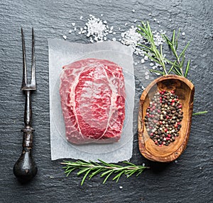 The top blade steak or beef steak on the graphite board with herbs and spices