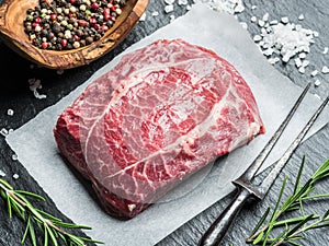The top blade steak or beef steak on the graphite board with herbs and spices