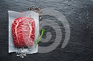 The top blade steak or beef steak on the graphite board with herbs and spices