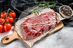 Top blade steak on a chopping Board, raw meat, marbled beef . Gray background. Top view