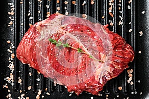 Top blade steak on a grill pan, raw meat, marbled beef . Black background. Top view