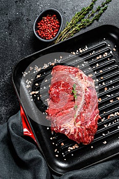 Top blade steak on a grill pan, raw meat, marbled beef . Black background. Top view