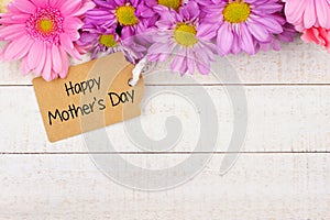 Top border of flowers with Mothers Day gift tag against white wood