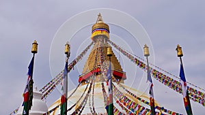 Top of Boudhanath stupa in the center of Kathmandu, Nepal, decorated with Buddhist prayer flags and five flagposts.