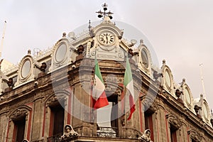 The top of building Edificio La Esmeralda with mexican flags, a clock, and many details and ornaments, Mexico City photo