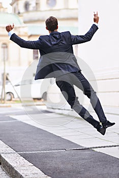 On top of the business world. Rearview shot of a businessman jumping for joy on a city sidewalk.