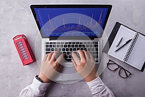 Top of businessman using laptop computer with stock chart market on screen.