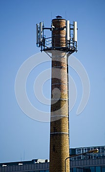 The top of a chimney with a cell phone antenna.