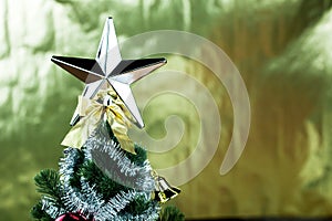 Top of Christmas tree decorated with star in bright golden shiny background