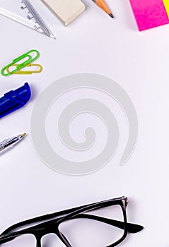 Top close up shot of stationary articles on a white surface with an eye glass for education and empowerment concept